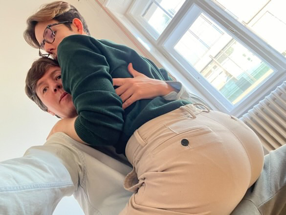 Close, playful hug between two people, one resting their head affectionately on the other's shoulder