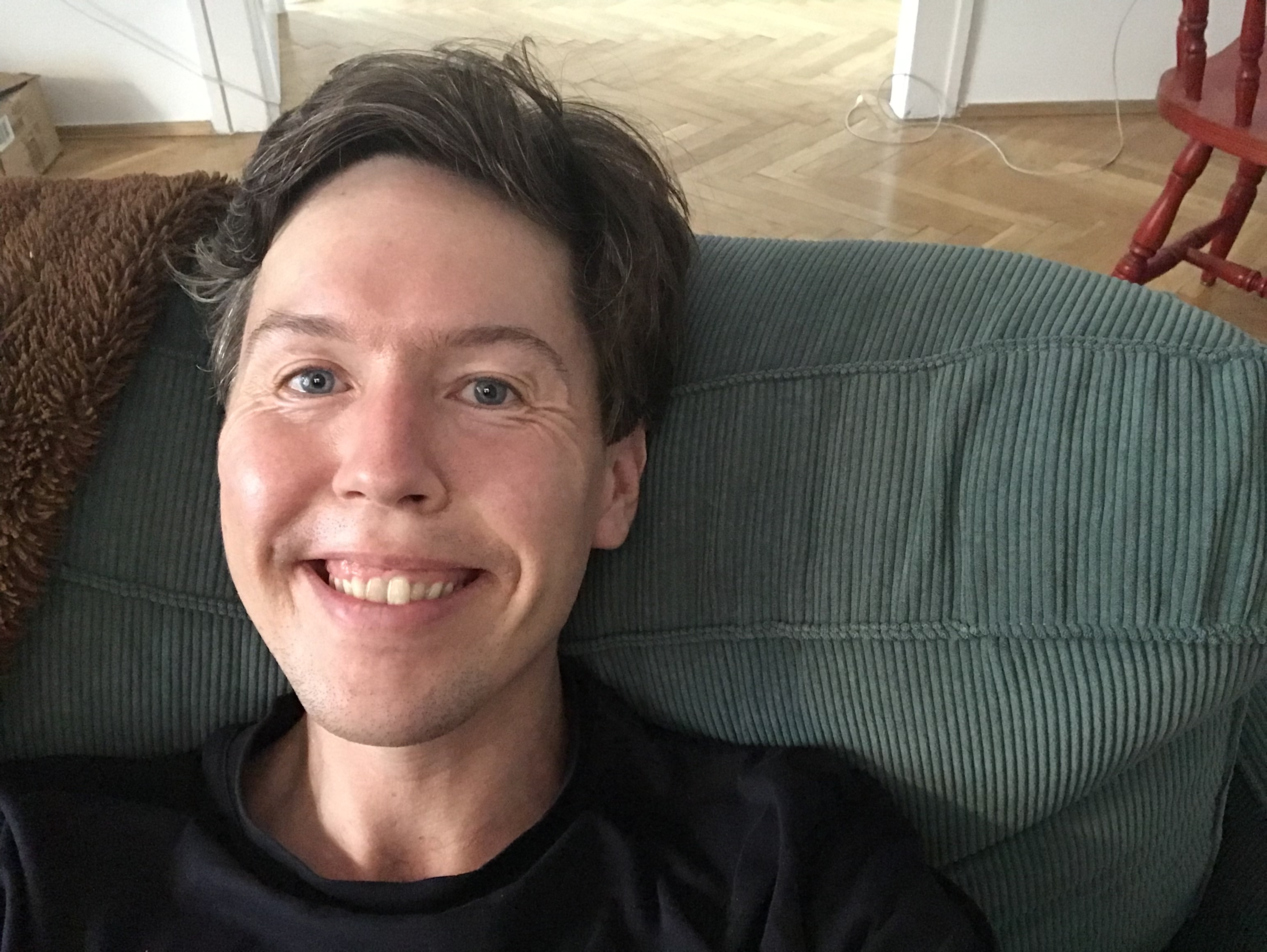 Smiling selfie lying on a green couch