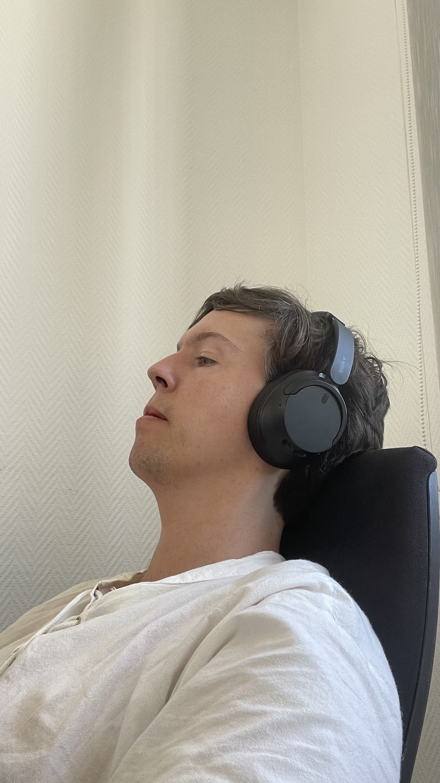 Side profile view of head resting against a chair headrest, showing neck posture
