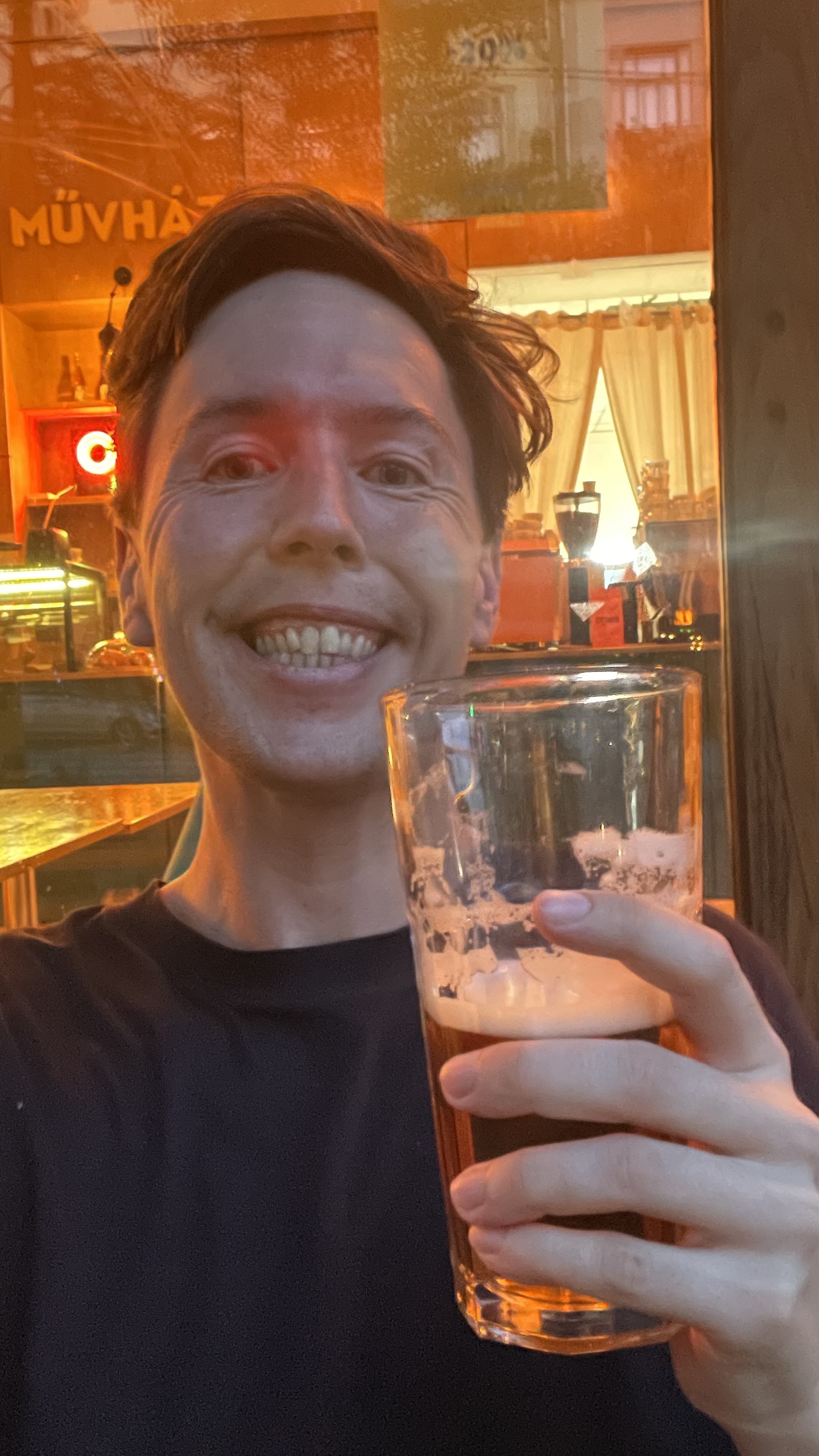 Selfie holding a glass of beer inside Muvhaz bar in Budapest