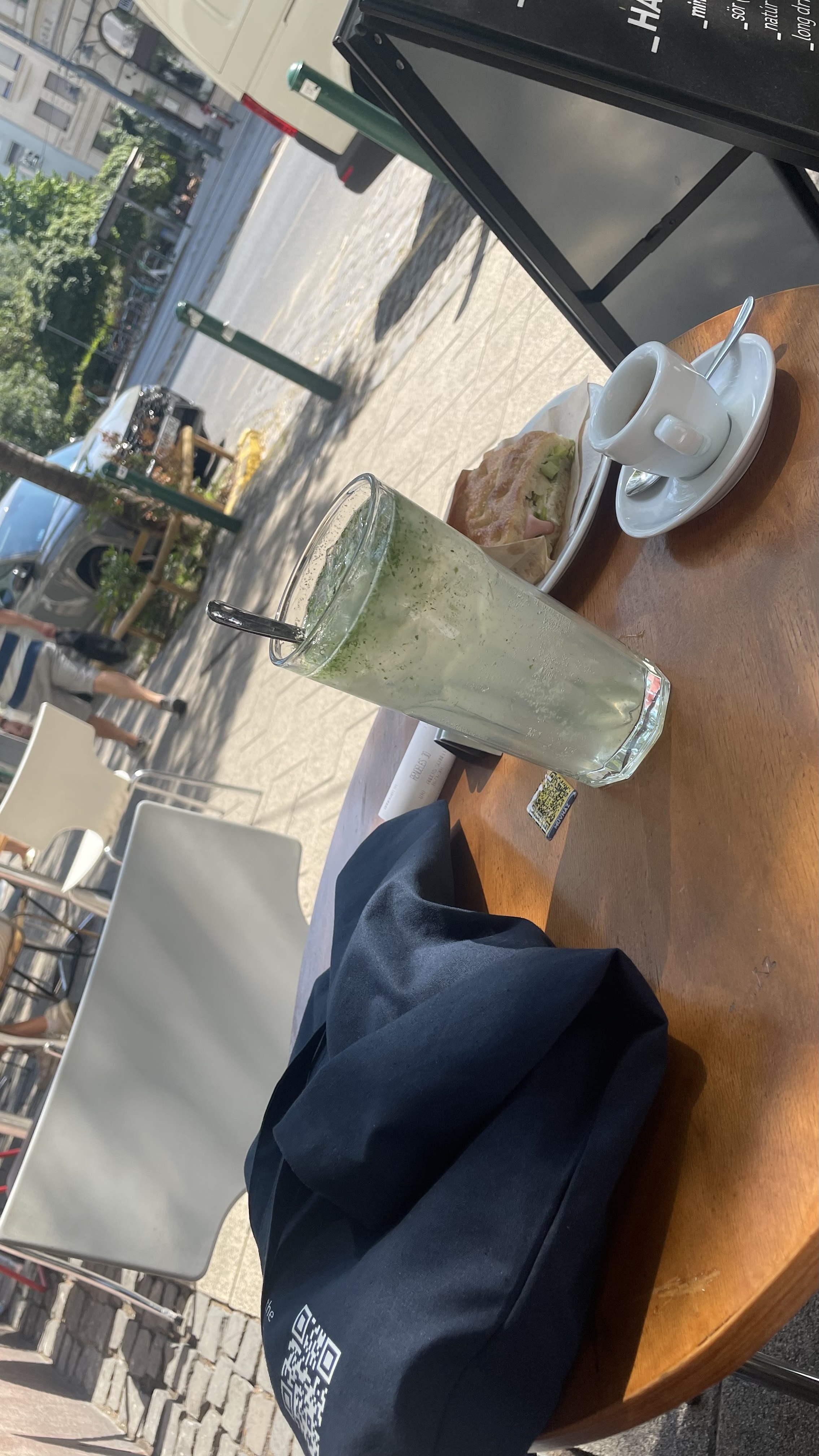 Beer mug on a cafe table at Muvhaz with a sunny courtyard, string lights, and outdoor seating visible through the window